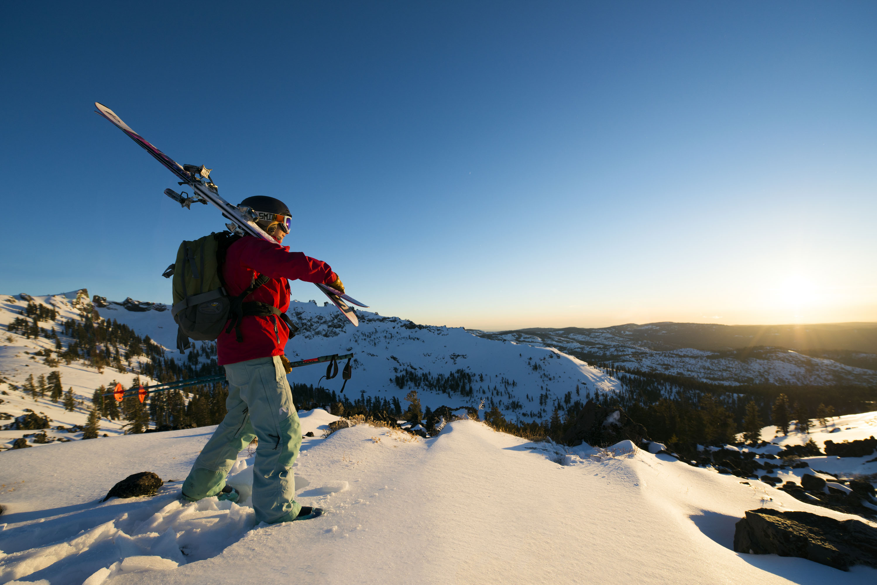 Skier stands along the ridgeline at Kirkwood Mountain Resort at sunset.