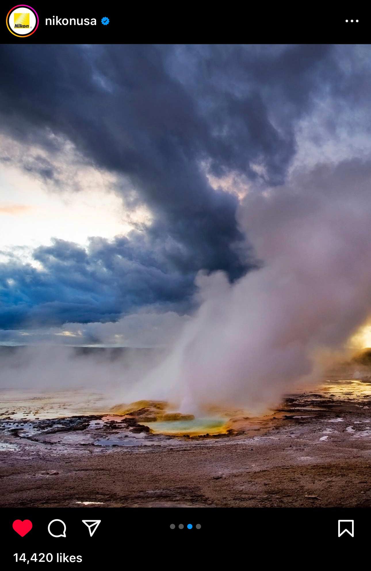 Steaming geyser under a dramatic sky shared by Nikon.