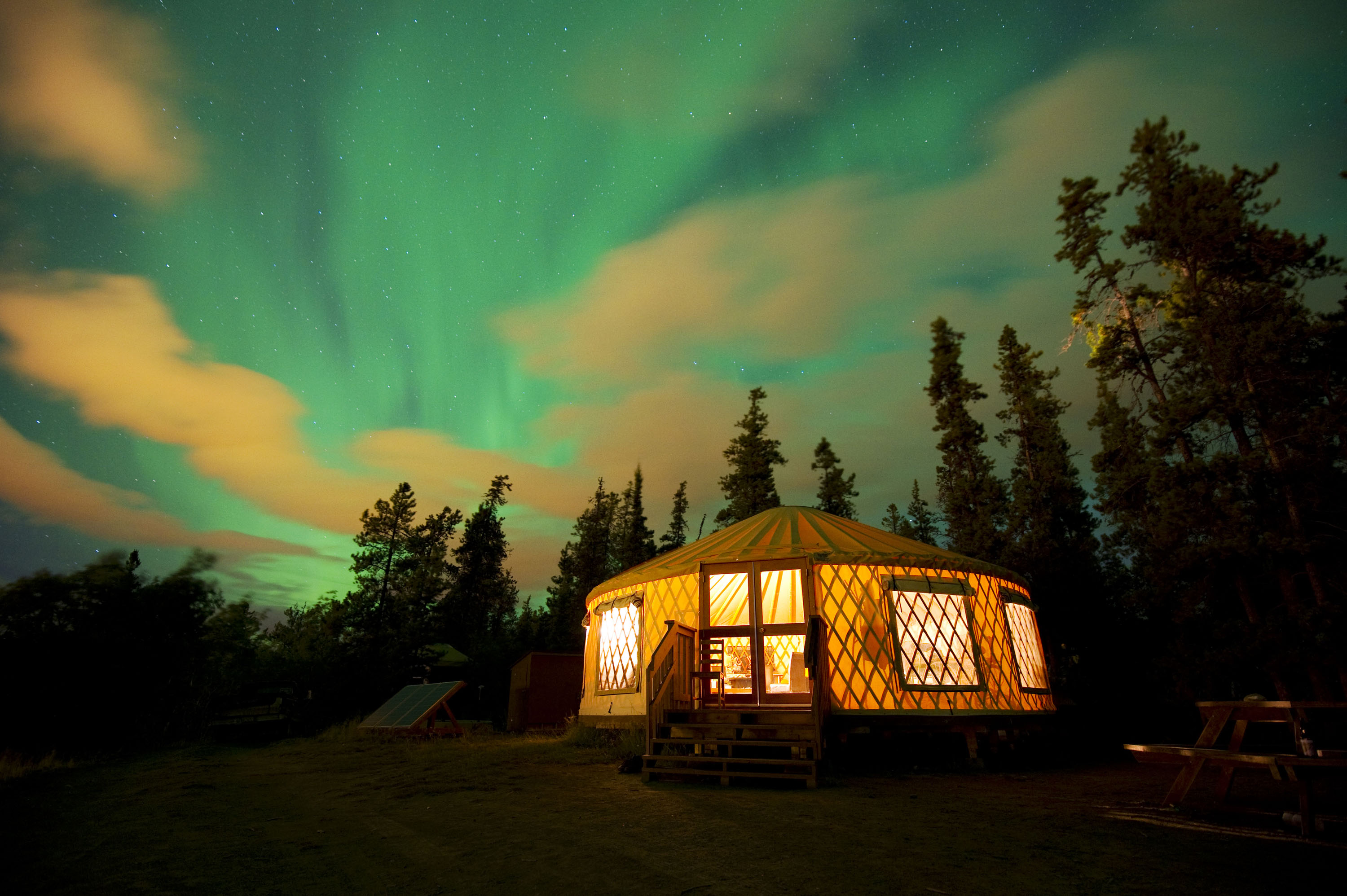 The Northern Lights over an illuminated yurt in the Yukon Territory, Canada.