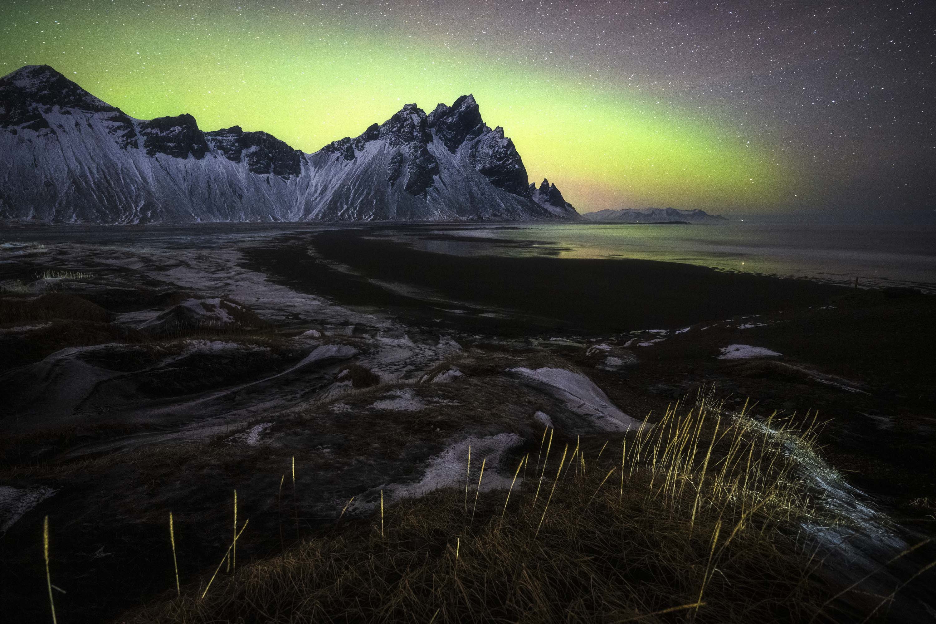 Northern Lights over snowy mountains near Stokksnes Iceland.